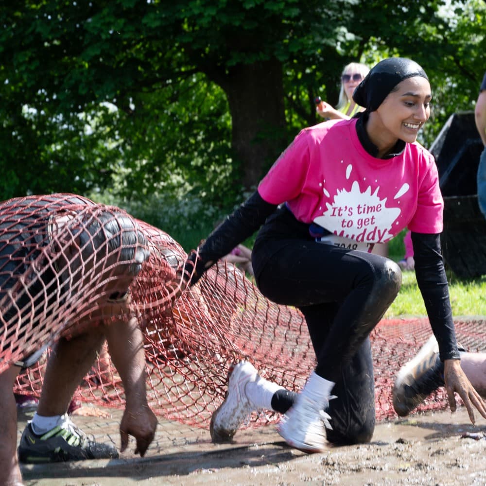 Pretty muddy supporter crawling in obstacle.