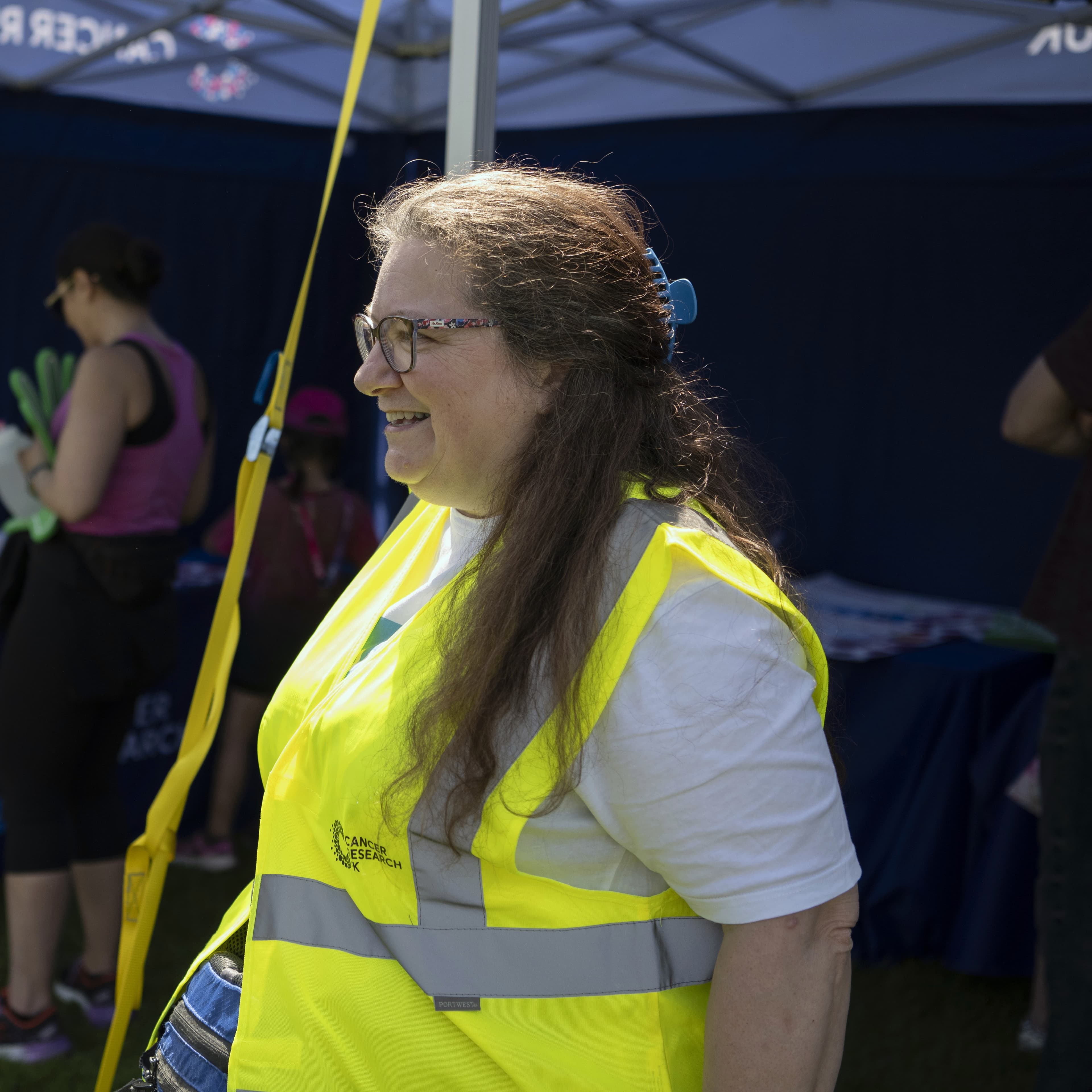 An Event Day Volunteer smiling and talking under a parasol.