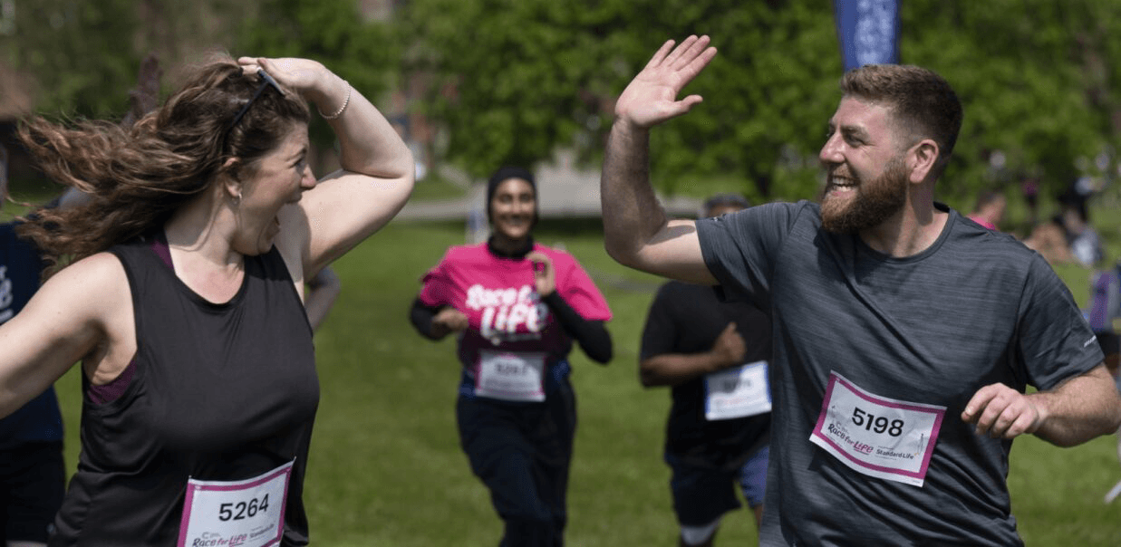 Race for Life participants running and smiling while giving each other a high five.
