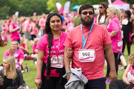 A photo of a couple wearing pink race for life t-shirts at 10k running event. They are wearing runners numbers and medals.