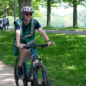 A smiling volunteer is cycling the course on their bike.